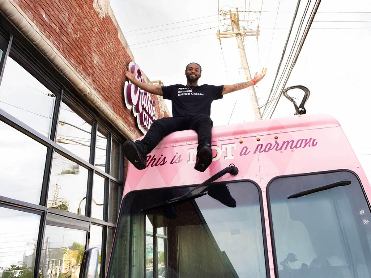 Ruthies cafe and Ruthies Food Truck and a Ruthies team member sitting on top of the Food Truck smiling