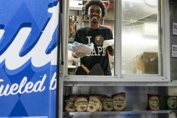 Ruthie’s For Good team member serving grilled cheese from food truck window at a Dallas event