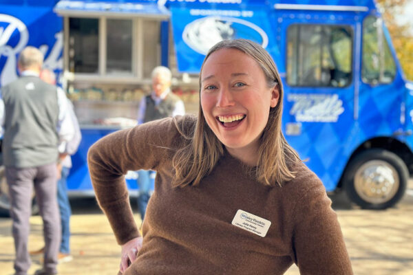 Event guest smiling in front of Ruthie’s For Good food truck at a Dallas catering event